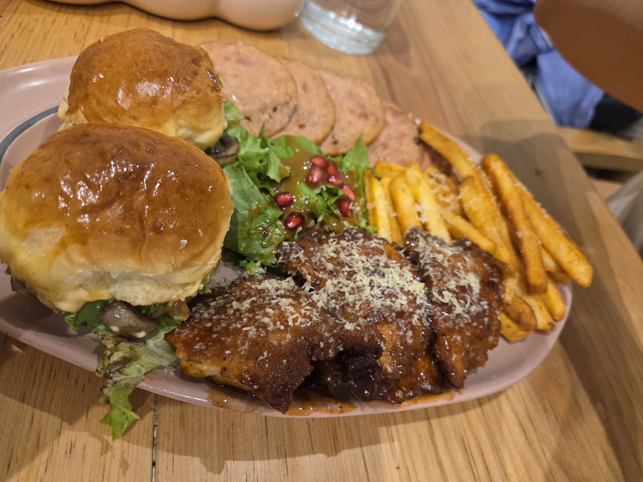 Grilled chicken sliders with salad and salt-and-pepper fries on a pink plate.