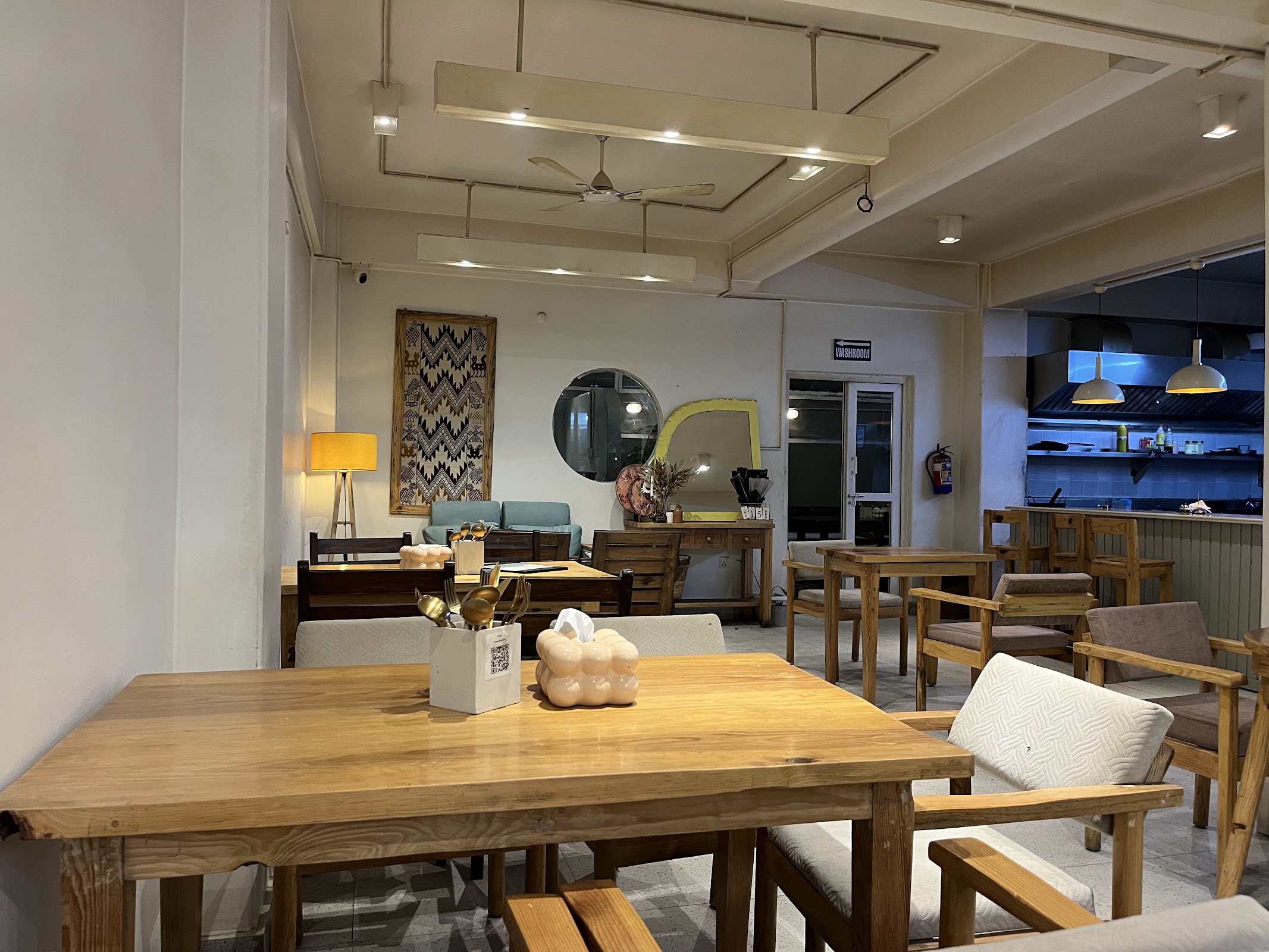 Inside the cafe at night — warm lights, wooden tables, traditional Nepali tapestry on the wall.